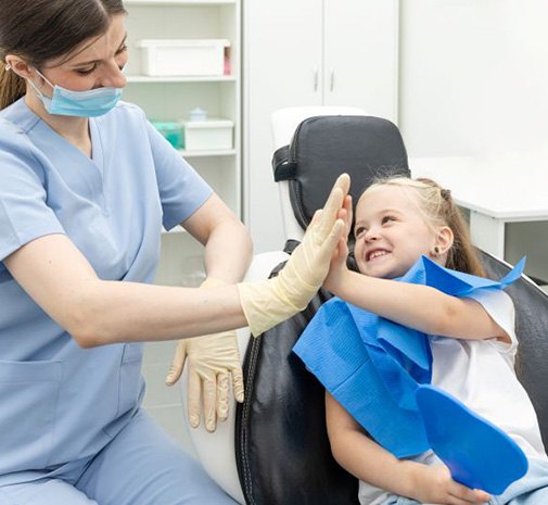 Happy child high-fiving dental team member