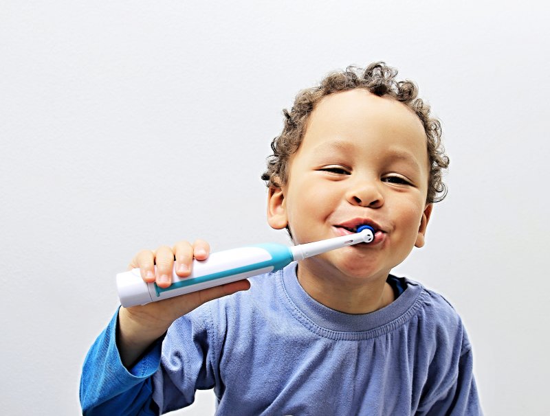 a little boy using an electric toothbrush