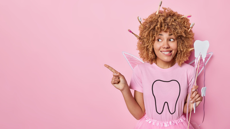 Woman dressed as the tooth fairy retrieving a lost tooth