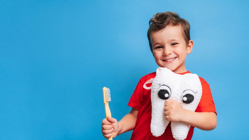 a little boy holding a toothbrush and tooth pillow